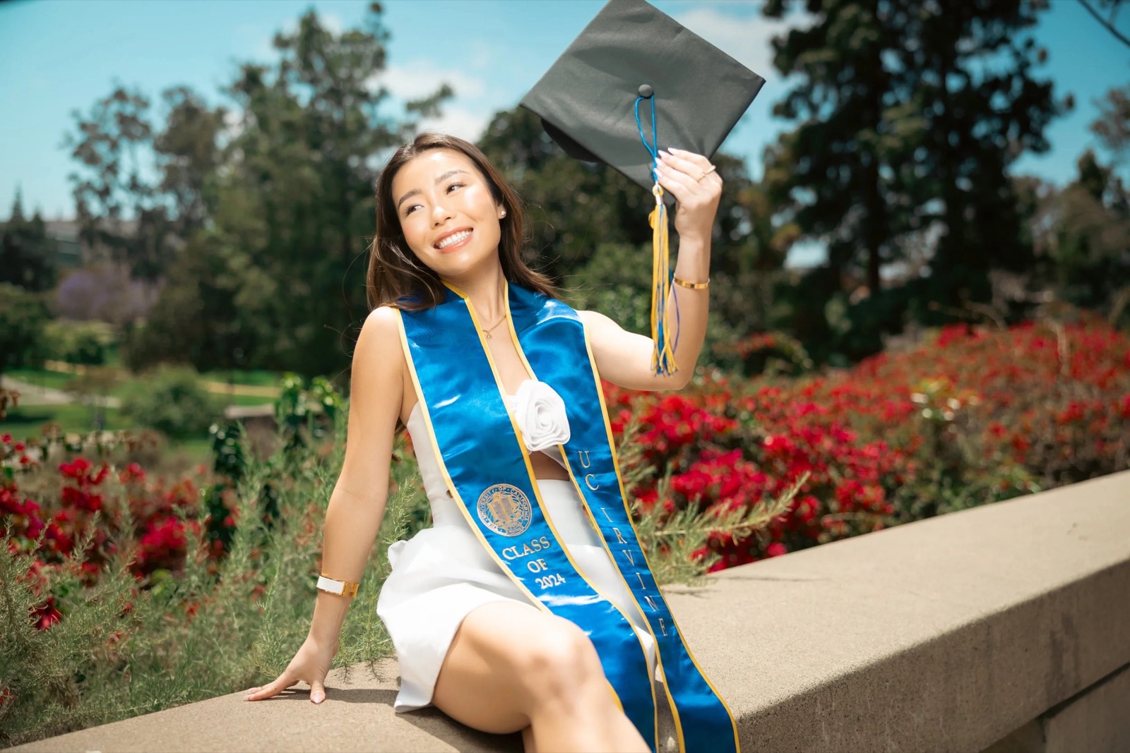 UCI graduate with red flower backdrop