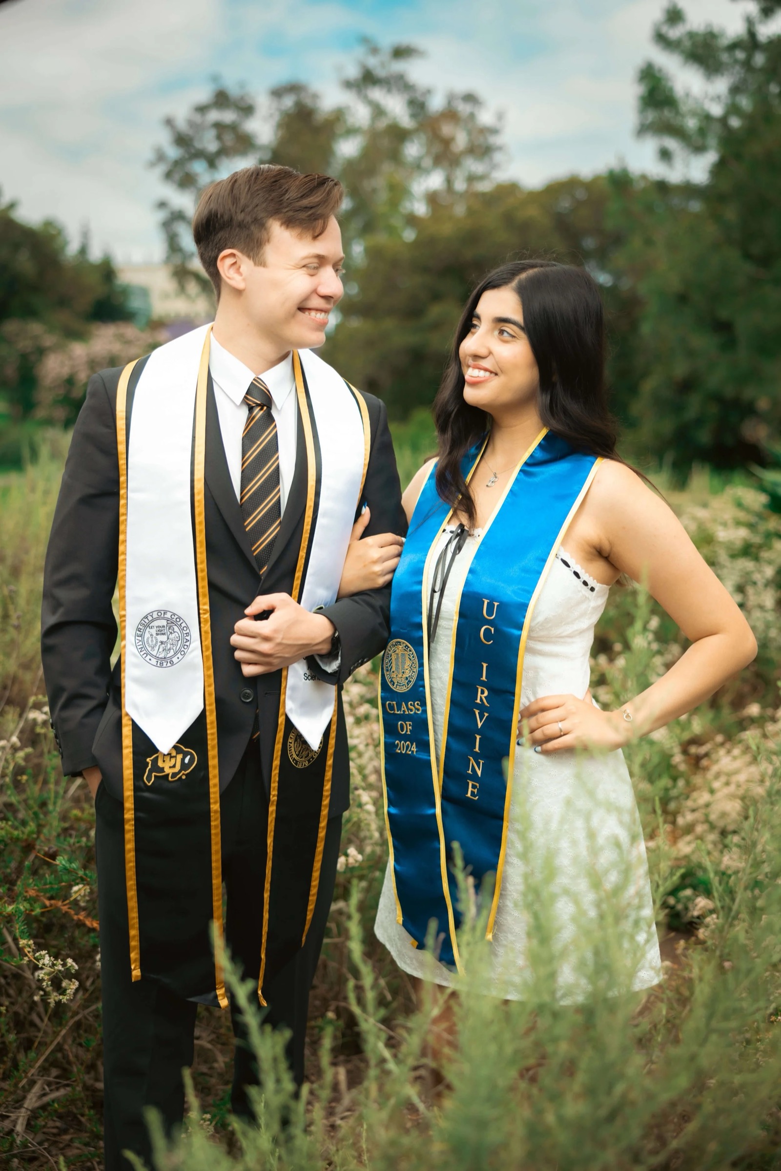 UCI graduate couple in front of red flowers
