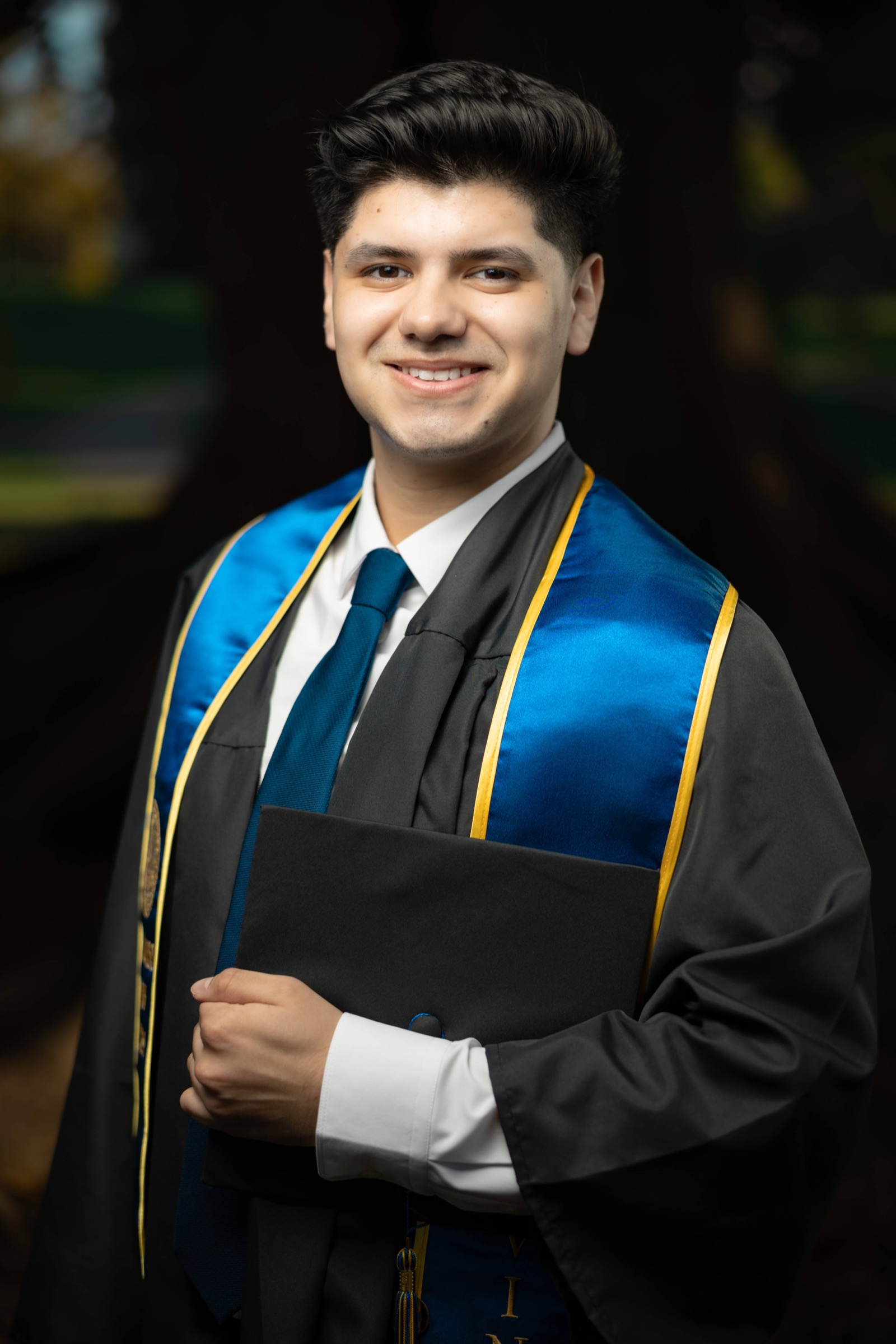 UCI graduate in cap and gown holding diploma folder