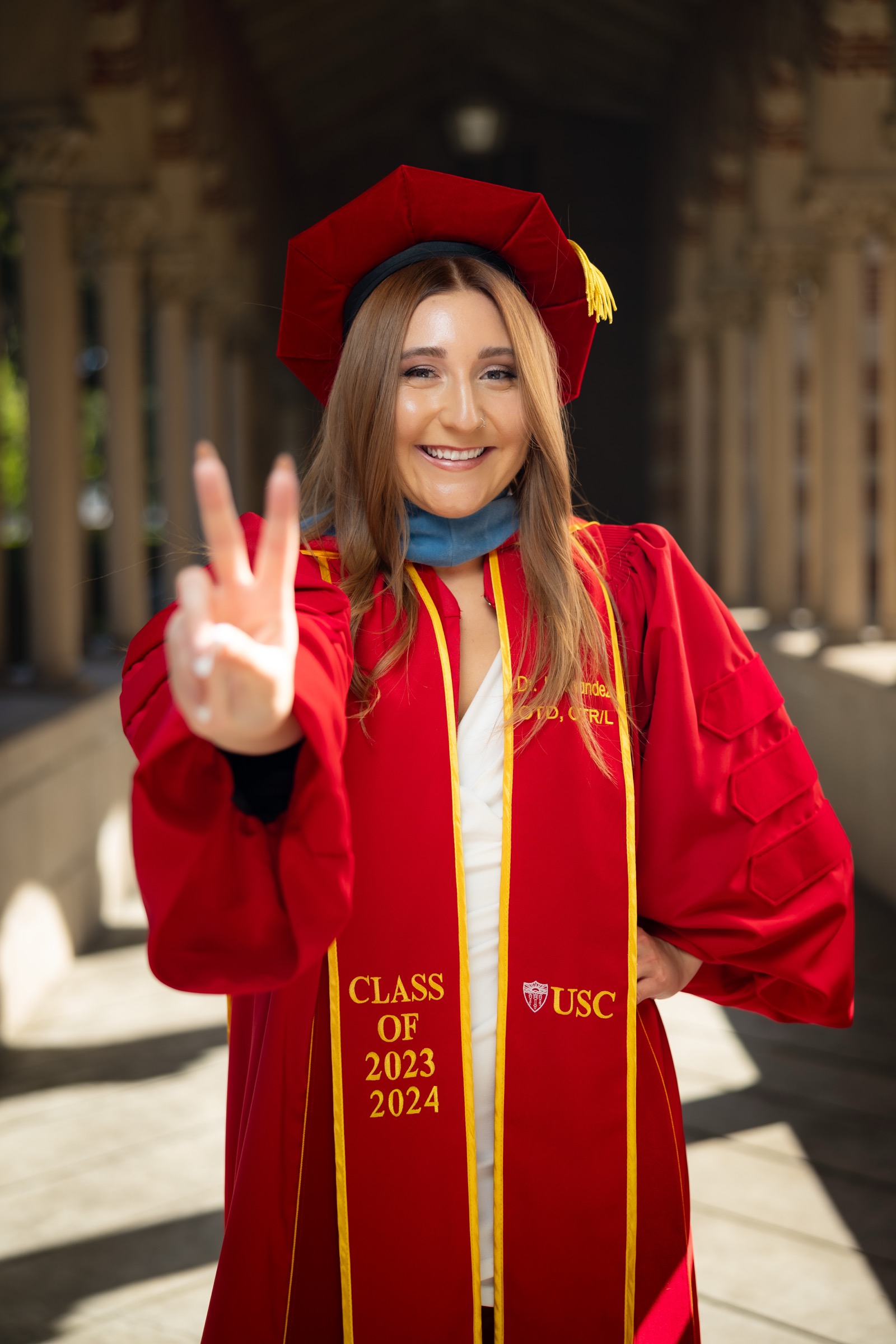UCI graduate in red dress with flowers