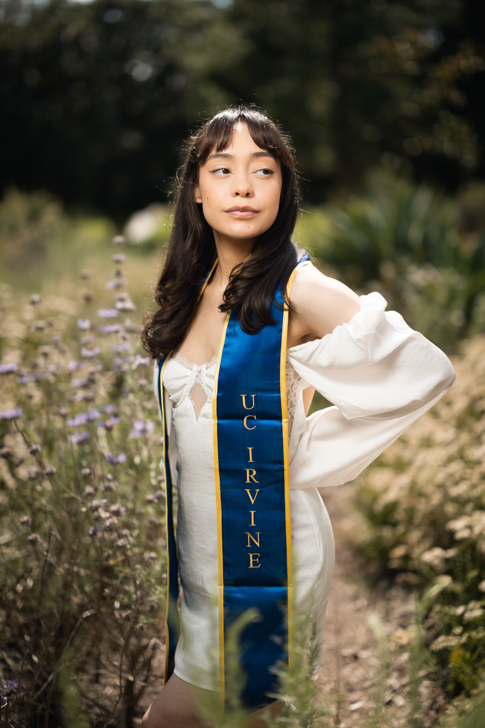 UCI graduate with sash and bougainvillea
